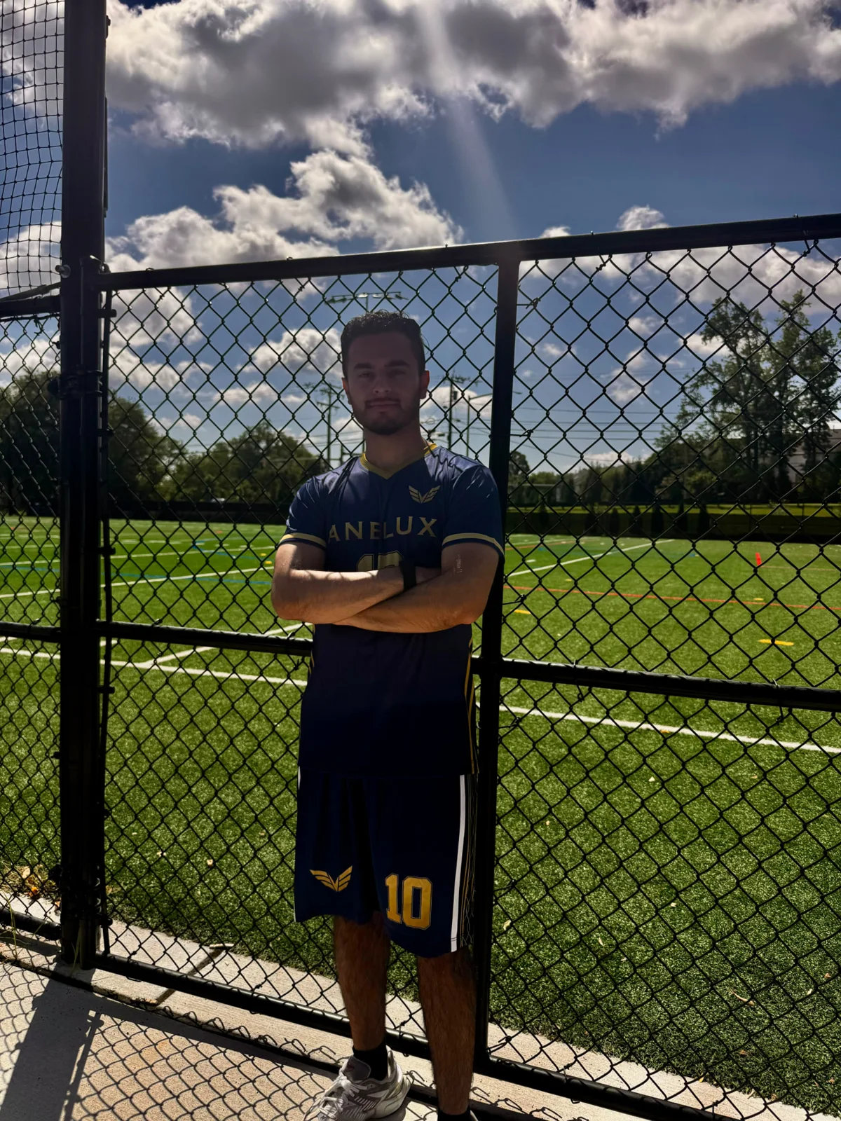 ANELUX athlete wearing a dark blue and gold number 10 soccer kit with arms crossed